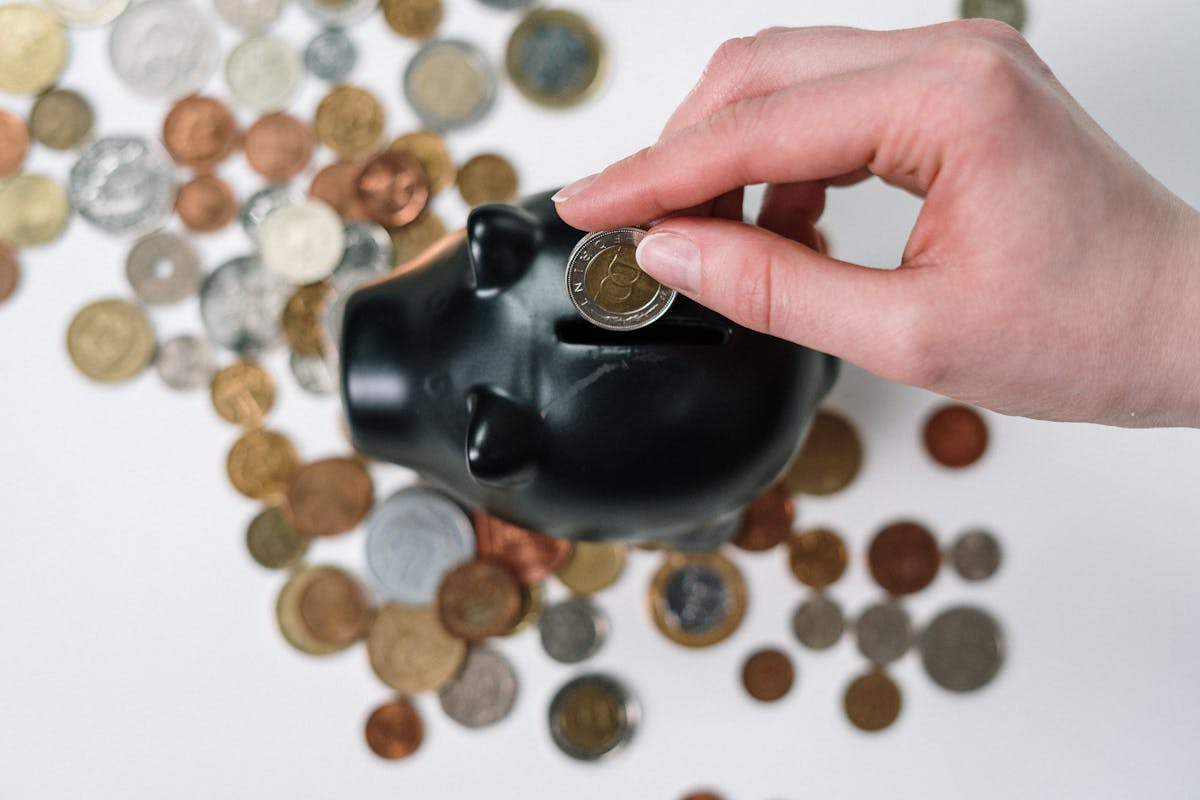 Person Putting Coin in a Piggy Bank