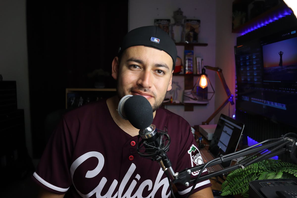 Man in Maroon Shirt Sitting at a Microphone