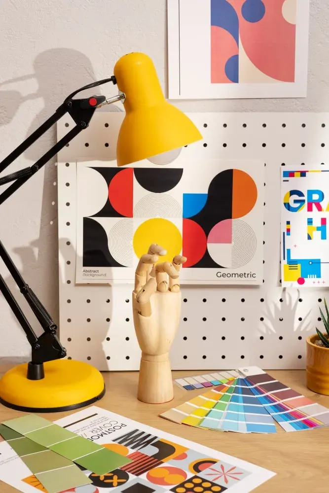 Bright creative desk with a geometric poster and a wooden hand model