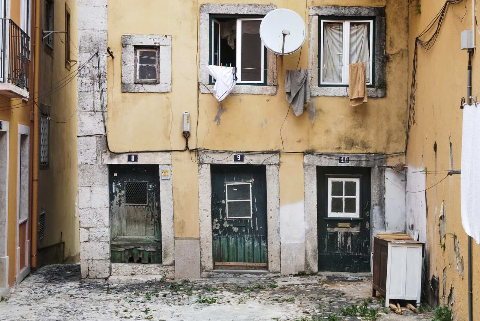 A-dilapidated-beige-colored-building-next-to-a-well-maintained-apartment-block-illustrating-a-value-add-investment-opportunity-min