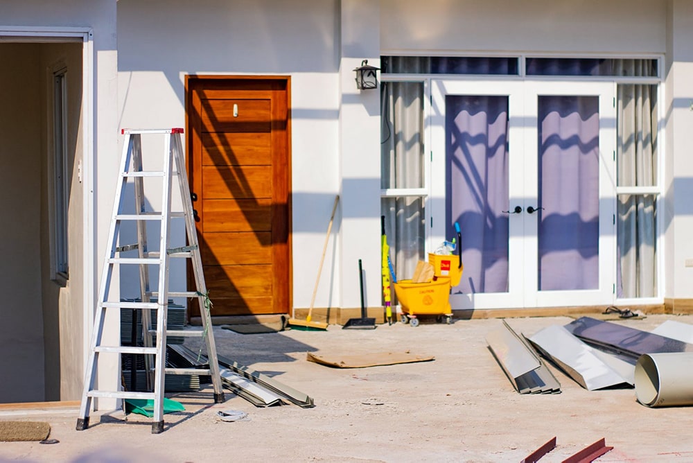 Building-materials-and-equipment-scattered-in-front-of-a-house-undergoing-renovations-min