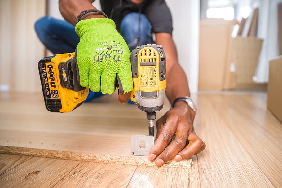 Upclose image of a handyman’s hand holding a power drill as he assembles wooden interior furnishings