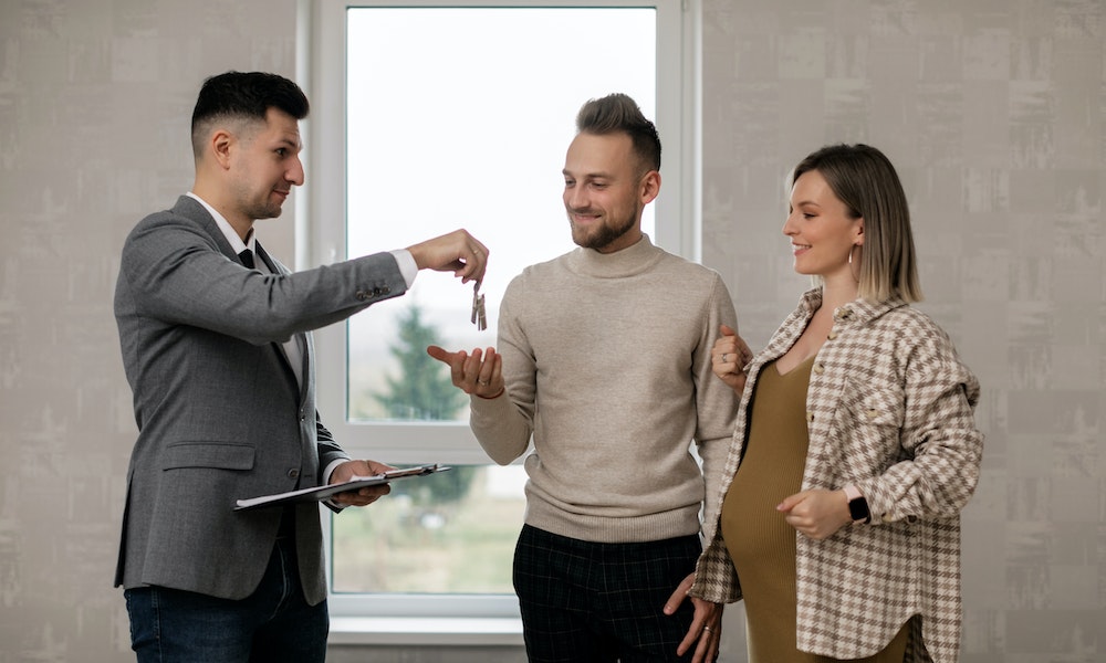 A real estate agent handing property keys to a happy home buyer couple