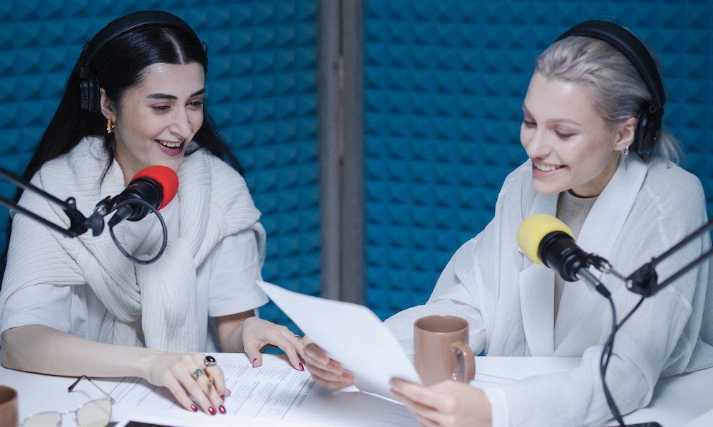 Female realtors comparing podcast notes in a studio