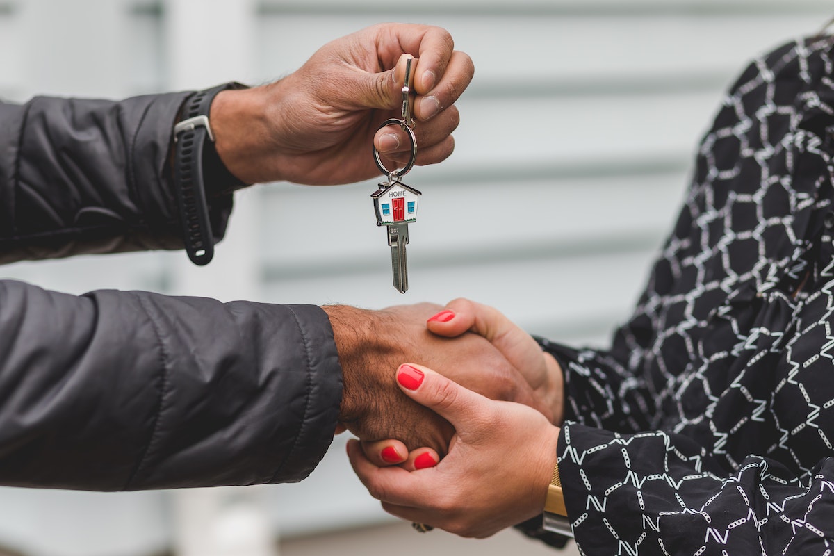 Successful real estate agent passing over house keys to homeowner.