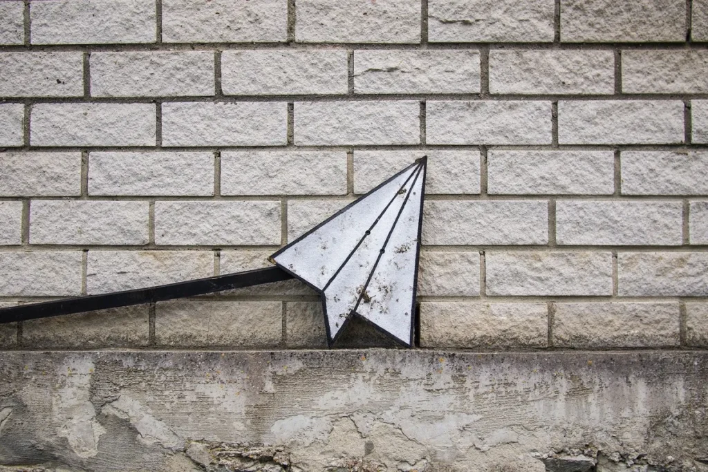 Image of a paper plane against a brick wall.