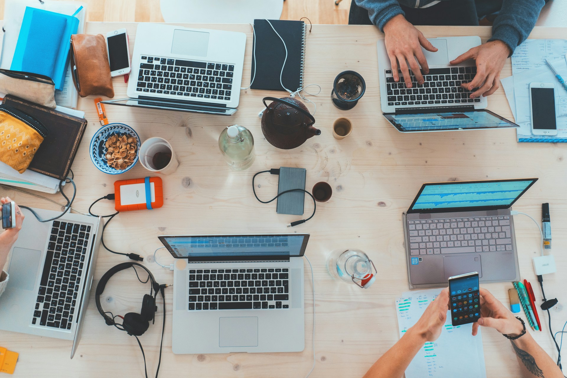 People sitting down near table with assorted laptop computers