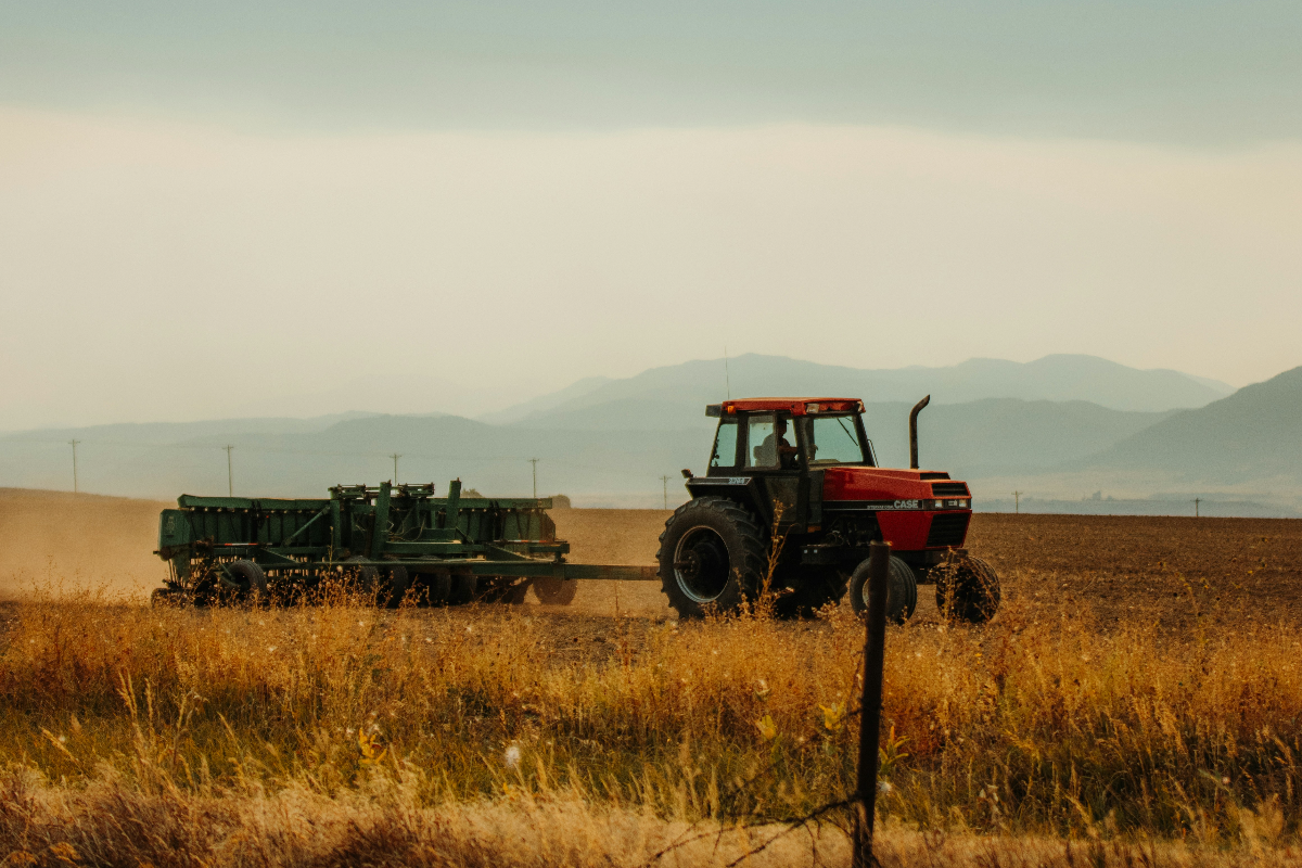 Red and black tractor on brown grass field during daytime