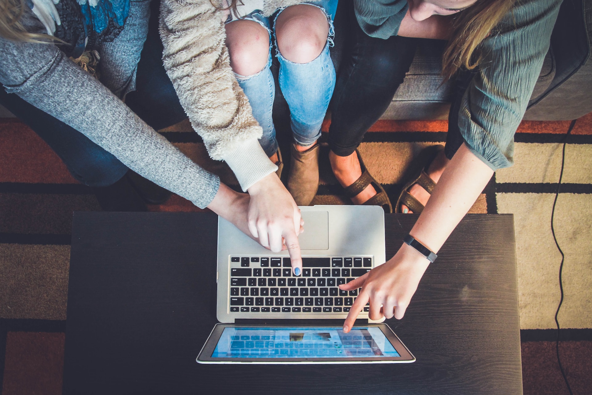 Three person pointing the silver laptop computer