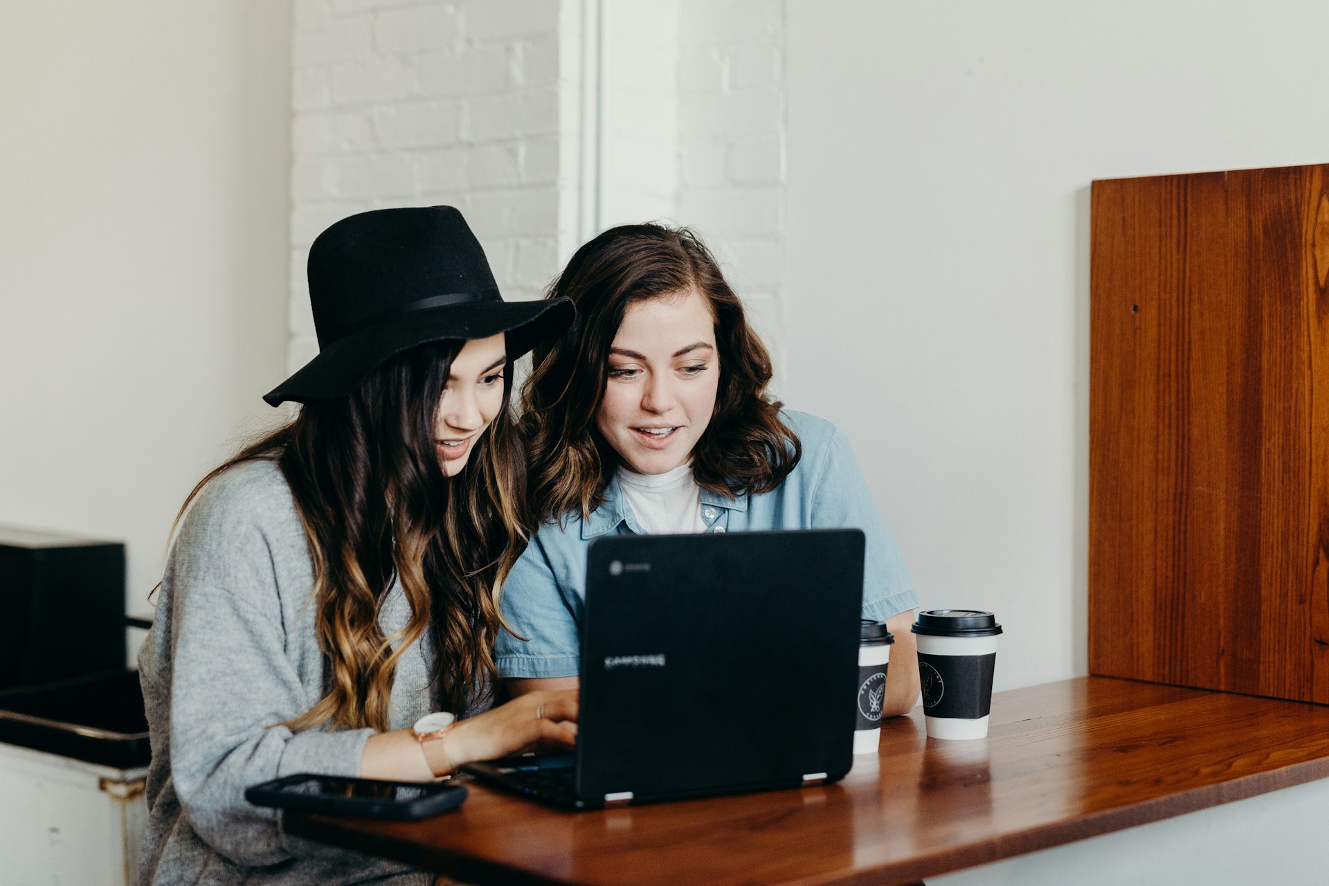 Two woman sitting near table using Samsung laptop photo