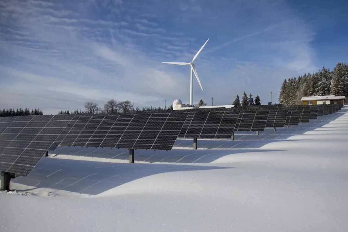 Solar Panels on Snow With Windmill Under Clear Day Sky