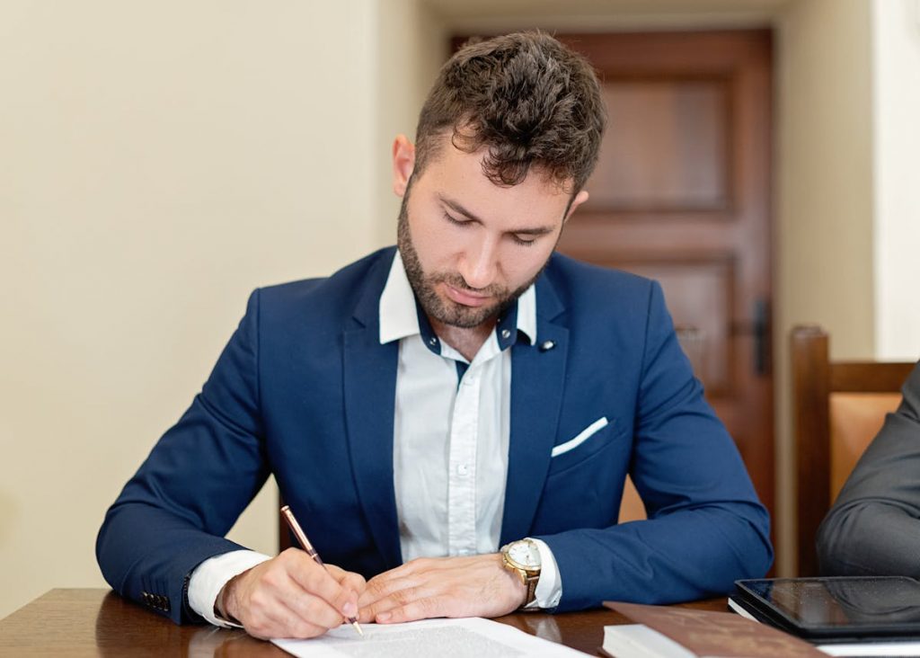 Man Sitting at a Table and Signing a Document