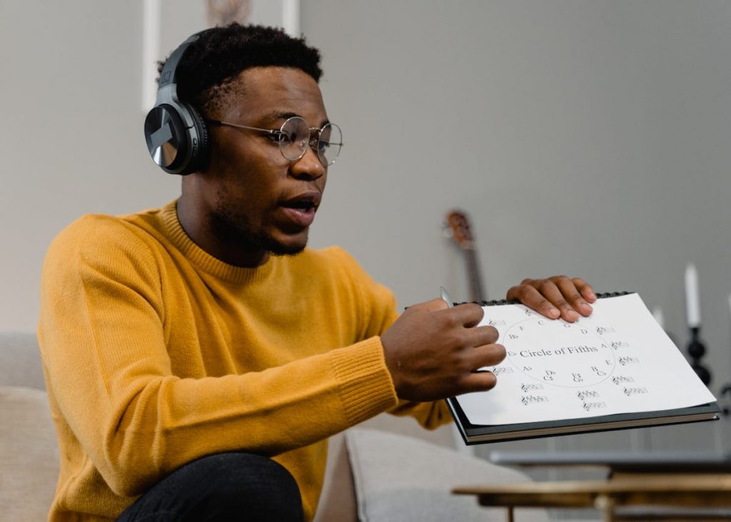 Man in Yellow Sweater Holding a Music Sheet