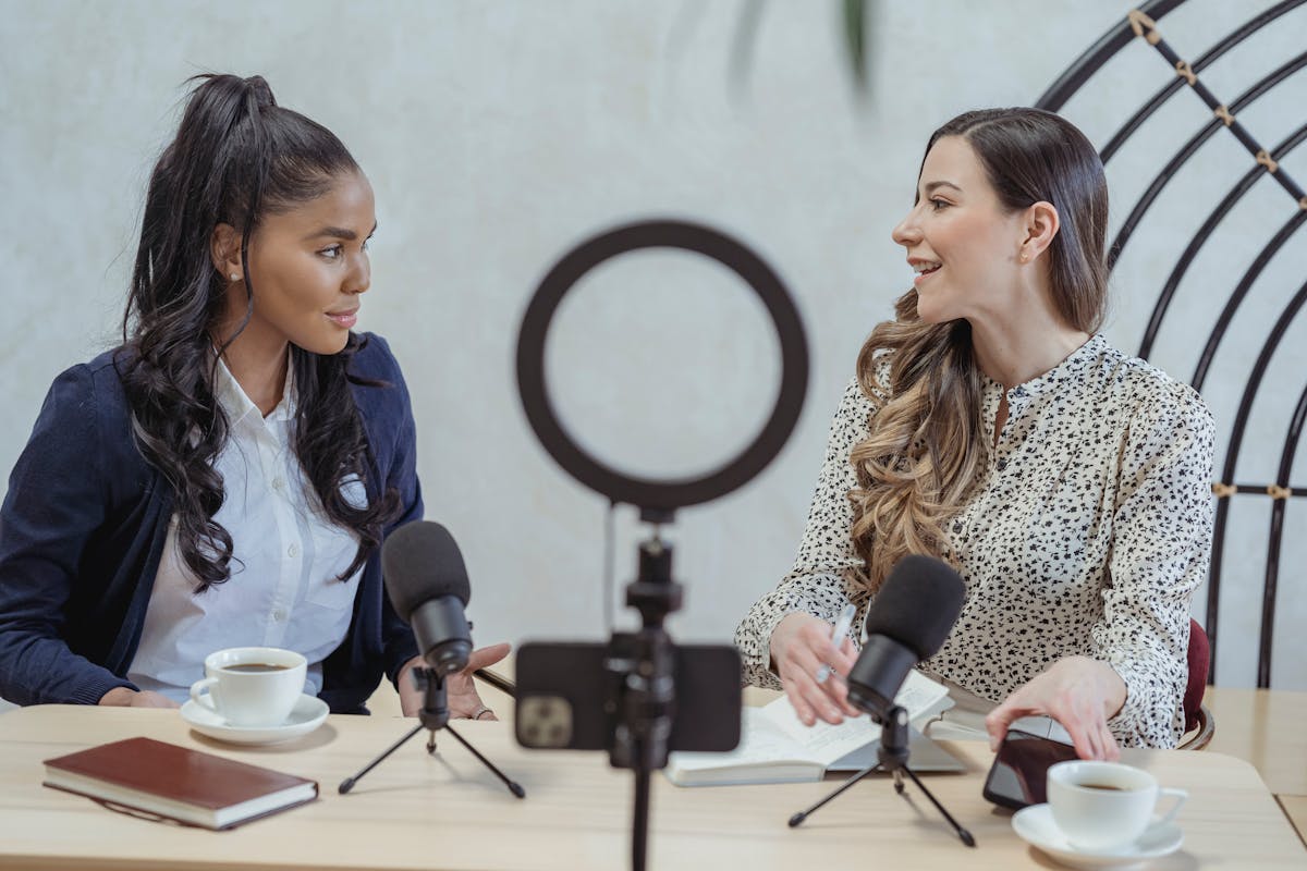 Smiling woman interviewing black female guest and recording video