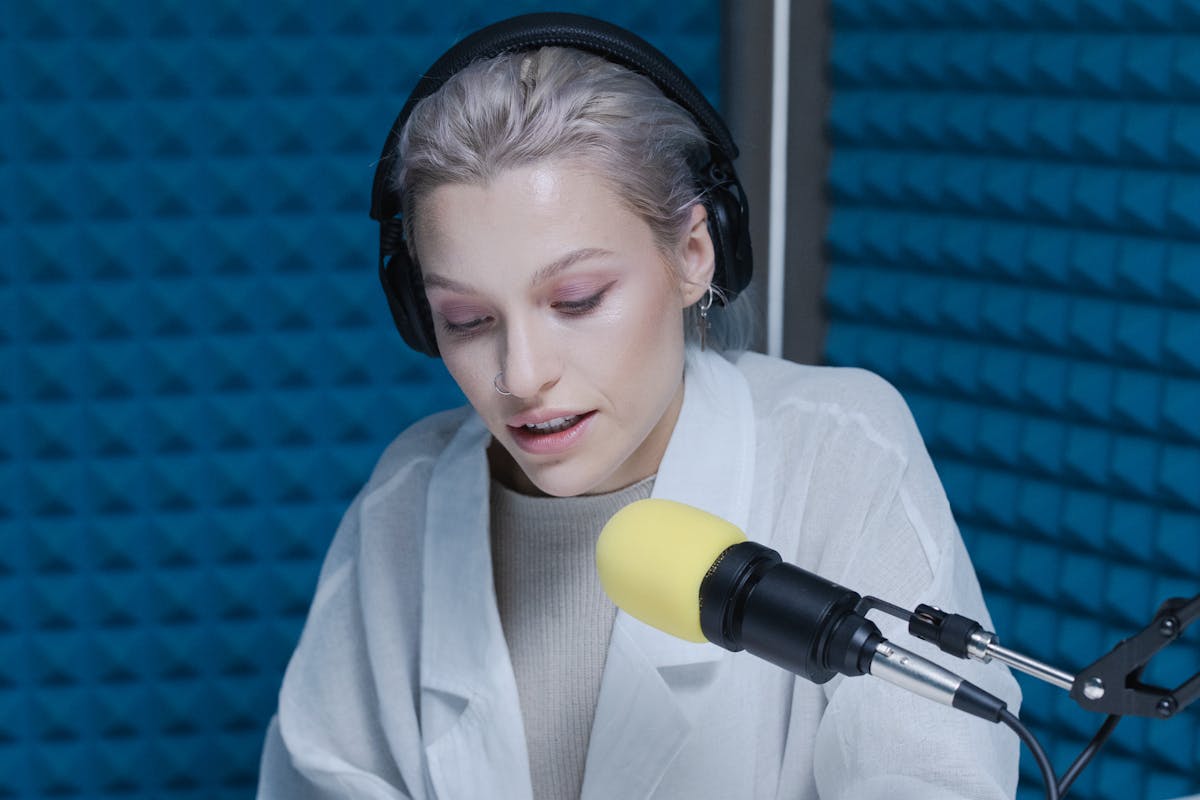 Woman Writing On Desk And Speaking With Podast Microphone